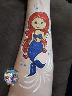 the little mermaid is painted on someone's arm and it looks like she has red hair