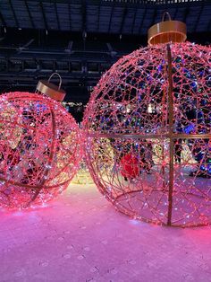 two large balls with lights on them in the middle of a floor covered in pink lighting