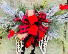 a christmas wreath hanging on the side of a building with red and black plaid ribbon