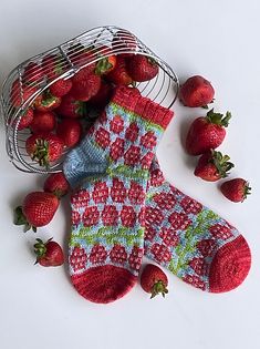 some strawberries are laying next to a pair of oven mitts and a wire basket