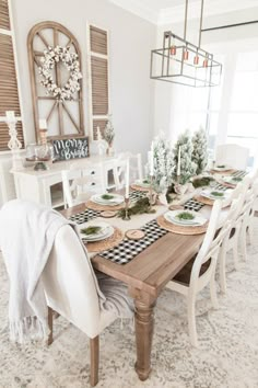 the dining room table is set with white chairs and black and white checkered placemats