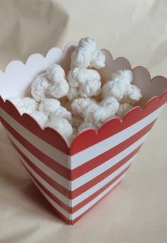 a red and white striped paper box filled with popcorn or marshmallows on a table