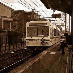 a man sitting on the side of a train platform as it pulls into a station