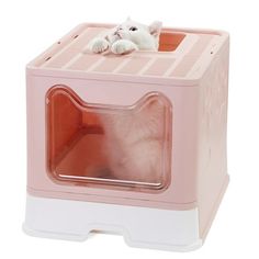 a small white cat sitting inside of a pink and white litter box with its paw on the door