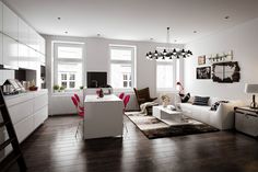 a living room filled with white furniture and lots of windows next to a wooden floor