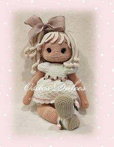 a crocheted doll is sitting on the floor with her legs crossed and wearing a dress