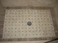 a tiled shower with a drain in the middle