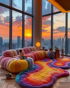 a living room filled with lots of furniture and large windows overlooking the city at sunset