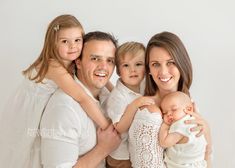 a man and woman holding two children in their arms while posing for a family photo