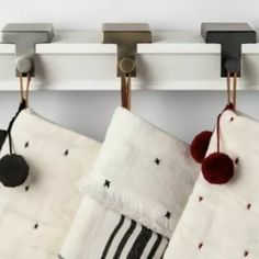 two kitchen towels hanging from hooks on the wall next to an oven mitt and towel rack