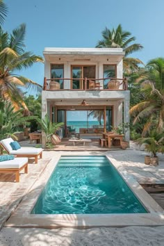 a house with a swimming pool in front of it and lounge chairs around the pool