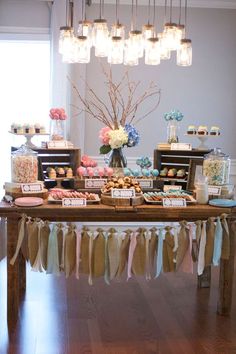 an image of a table with desserts on it and decorations hanging from the ceiling