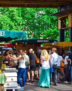 a group of people standing in front of a market stall with food on it's tables