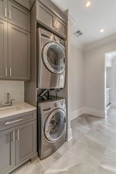 a washer and dryer are in the middle of a kitchen with gray cabinets