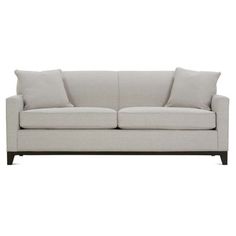 a white couch with two pillows on it's back and one arm facing the camera