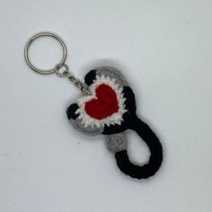 a crocheted keychain with a red heart on it and a black handle