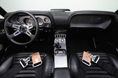 the interior of a sports car with black leather seats and steering wheel, including two pedals