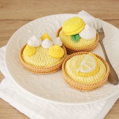 three small crocheted pastries on a white plate with a fork and knife