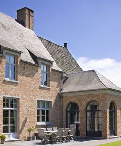 a large brick house sitting on top of a lush green field