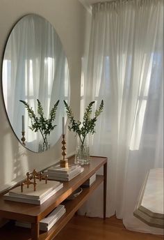 two vases with flowers are sitting on a table in front of a round mirror