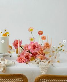 a table topped with a white cake and lots of pink flowers on top of it