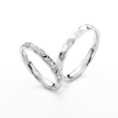 two white gold wedding rings with diamonds on each side, set against a white background