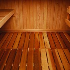 the inside of a wooden sauna with wood flooring and shelves on each side