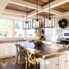 a kitchen with white cabinets and wooden floors, an island table surrounded by chairs in the center