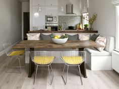 a kitchen and dining room with white walls, wood flooring and wooden table surrounded by yellow chairs