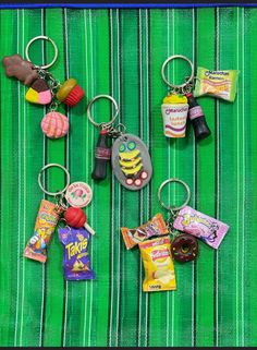 several different key chains with candy and candies on them sitting on a green striped cloth