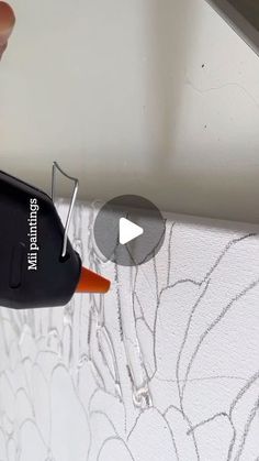 someone is painting a wall with white paint and black marker on the bottom half of it