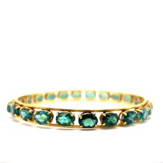 This statement bangle bracelet features a a collection of green tourmalines in 18 karat yellow gold. One of a kind and stylish. Twenty-four (24) 1.35 carat oval cut tourmalines decorate the 8.5 inch bangle. Radiant & timeless in design. A structured style of modern bangle to add a pop of color to your wardrobe. A great gift for jewelry lovers. Tourmaline gemstones symbolize active compassion, vitality, and abundance. A chic gift for any special occasion! Pink Tourmaline Jewelry, Modern Bangle, Rose Gold Bangle Bracelet, 18k Gold Bangle, Flush Set Diamond, Rose Gold Bangle, Sterling Silver Bangle Bracelets, Tourmaline Jewelry, Gold Bracelet For Women