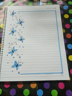 a notebook with butterflies drawn on it sitting on a polka dot tablecloth covered surface