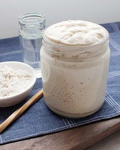 a wooden table topped with a mason jar filled with white powder next to a spoon