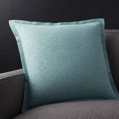 a grey couch with a green pillow on it and a black wall in the background