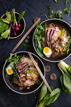 two bowls filled with meat and vegetables next to chopsticks on top of a table