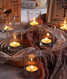 there are many candles that are in the glass vases on the table with other items