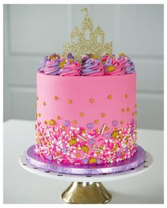 a pink and purple cake with a gold crown on top