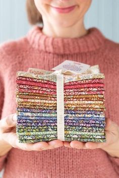 a woman holding a stack of multicolored cloths