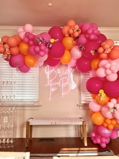 a bunch of balloons that are hanging from the ceiling in a room with a bench