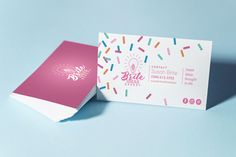 a pink and white business card with sprinkles on the front next to it