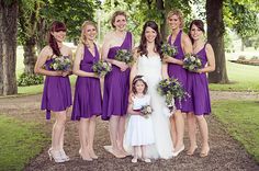 a group of women in purple dresses standing next to each other