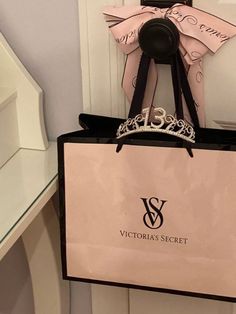 a pink and black shopping bag hanging from the side of a door with a tiara on it