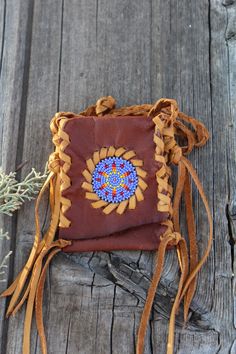 A beaded amulet bag made in rust colored leather with saddle lace. This small beaded pouch measures approximately 4 inches tall x 3 inches wide and has a braided neck strap that measures 28 inches. This is a very beautiful necklace bag where you can keep something very special close to your heart. Props are not included. This item is MADE TO ORDER. You will not receive the piece you see in the photos, we will make one similar for you. Please allow 3 to 4 weeks to ship and take the time to read o Bohemian Hand-stitched Shoulder Bag As Gift, Beaded Brown Shoulder Bag Gift, Brown Bohemian Bag For Personal Use, Bohemian Brown Bag For Personal Use, Handmade Spiritual Bag For Festivals, Bohemian Beaded Shoulder Bag For Gift, Small Beaded Necklace, Leather Medicine Pouch, Amulet Bag