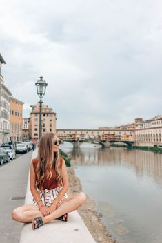 a woman sitting on the edge of a bridge