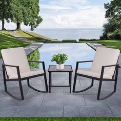 two chairs sitting next to each other on top of a stone floor near a pool