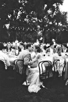 a black and white photo of people sitting around a table at a formal dinner party