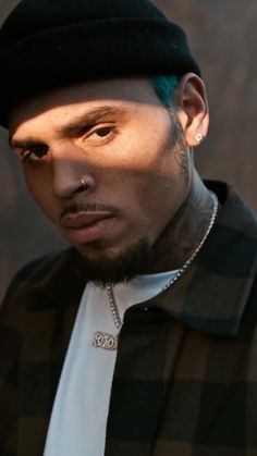 a man with green hair and piercings wearing a black hat looking at the camera