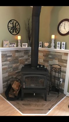 a wood burning stove sitting inside of a living room next to a wall with pictures on it