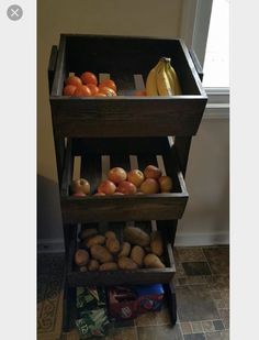 a wooden crate filled with lots of fruit on top of a tiled floor next to a window